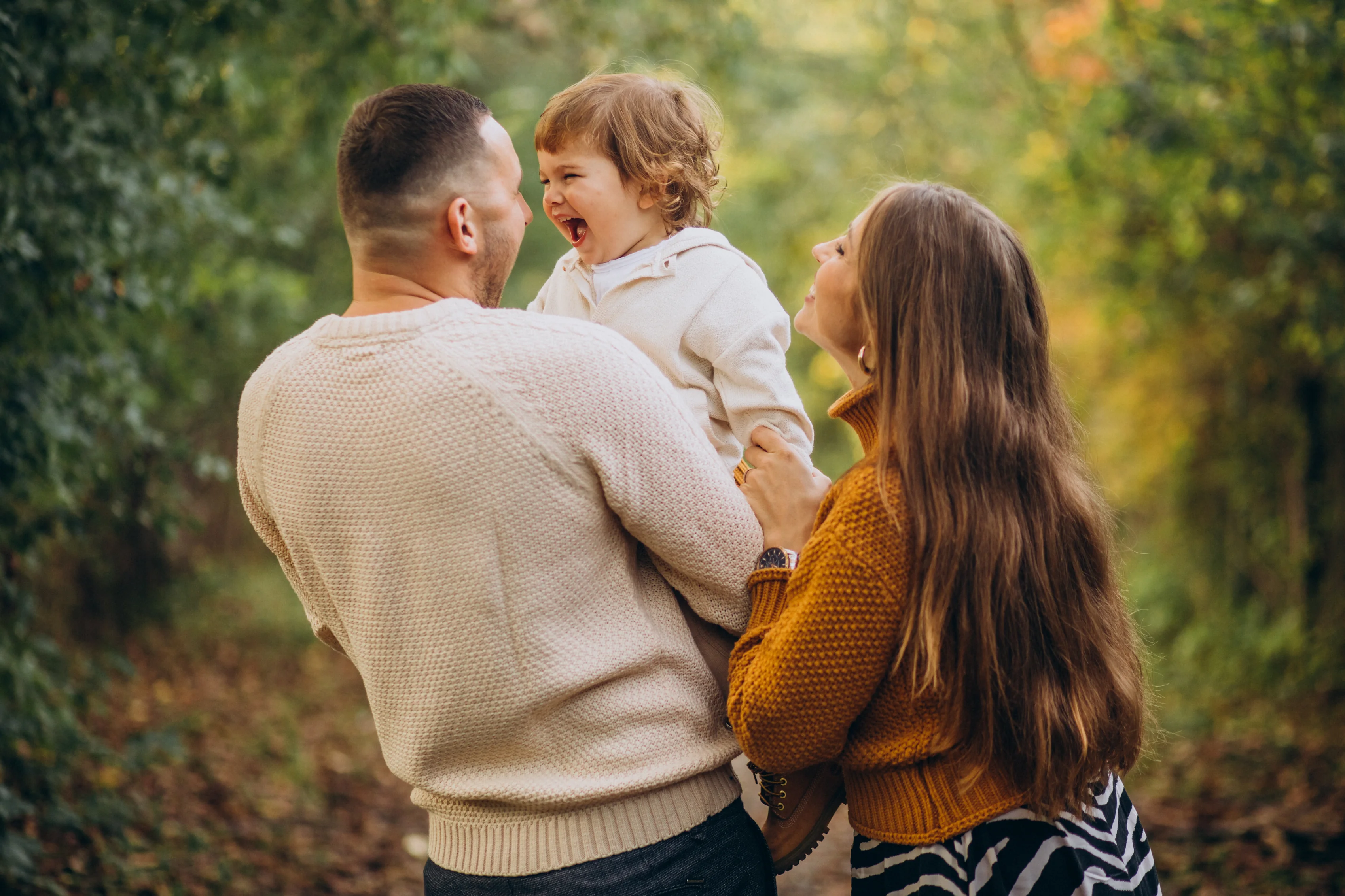 Parents laughing with their young child on an autumn walk