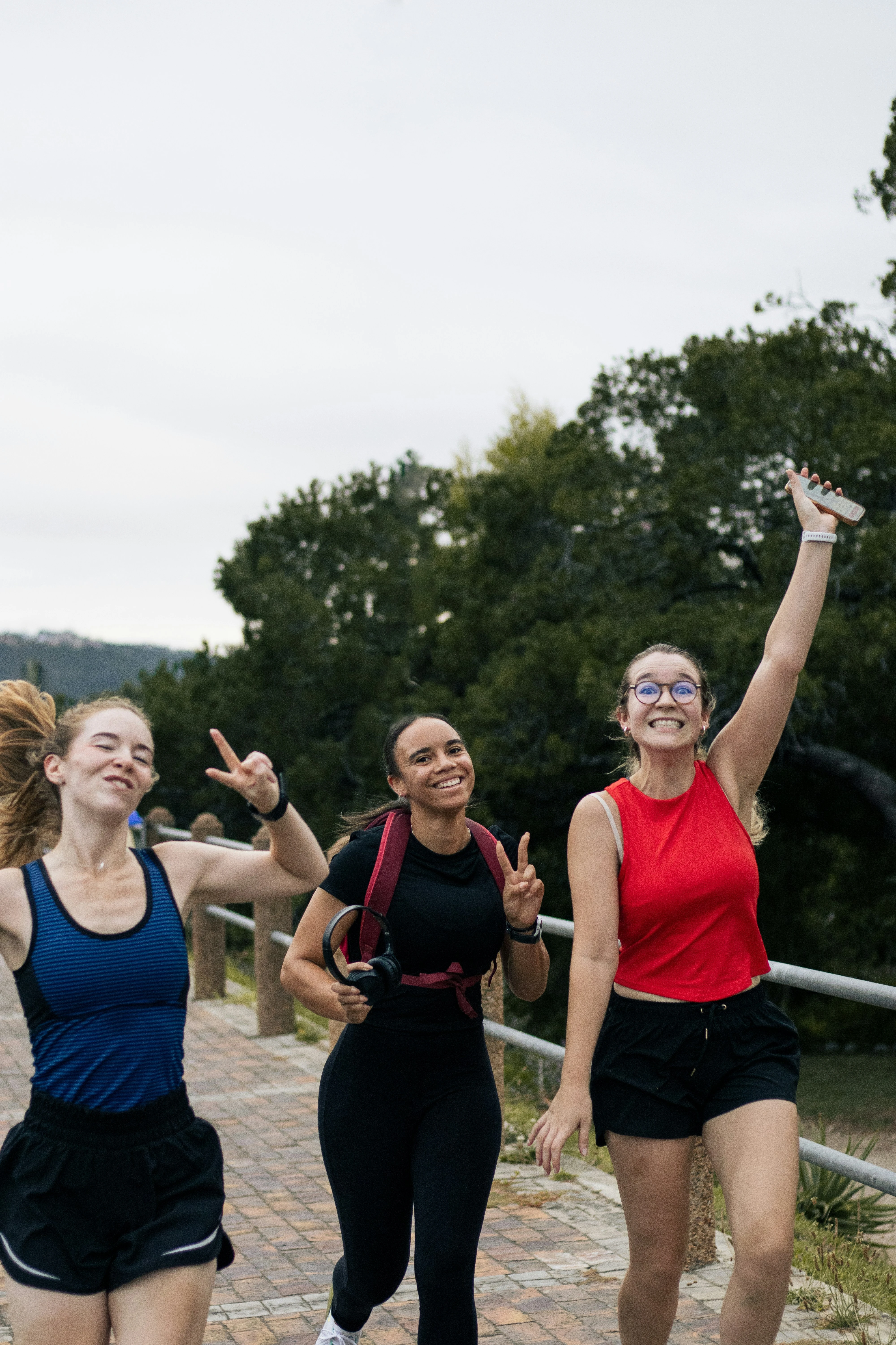 Three friends laughing and waving on an outdoor walking path
