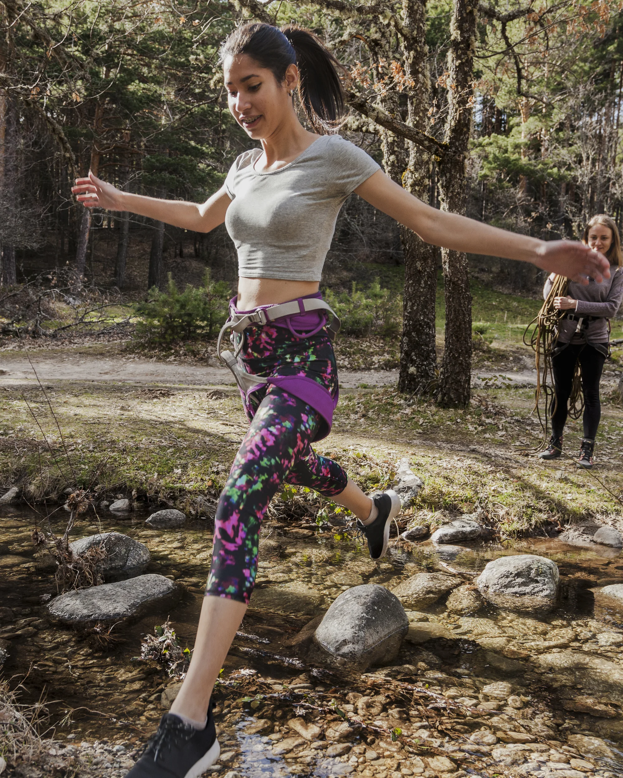 A woman leaping across stepping stones in a creek